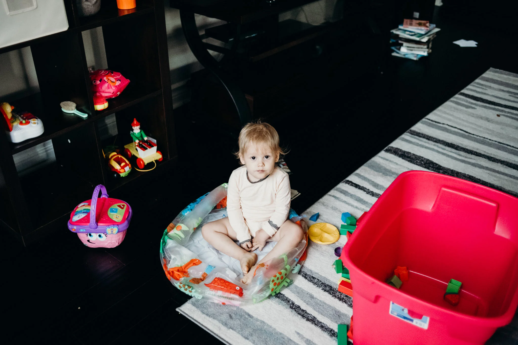 Packing up the last of Leya’s toys. She sits inside her now deflated bath tub that used to hold her blocks.