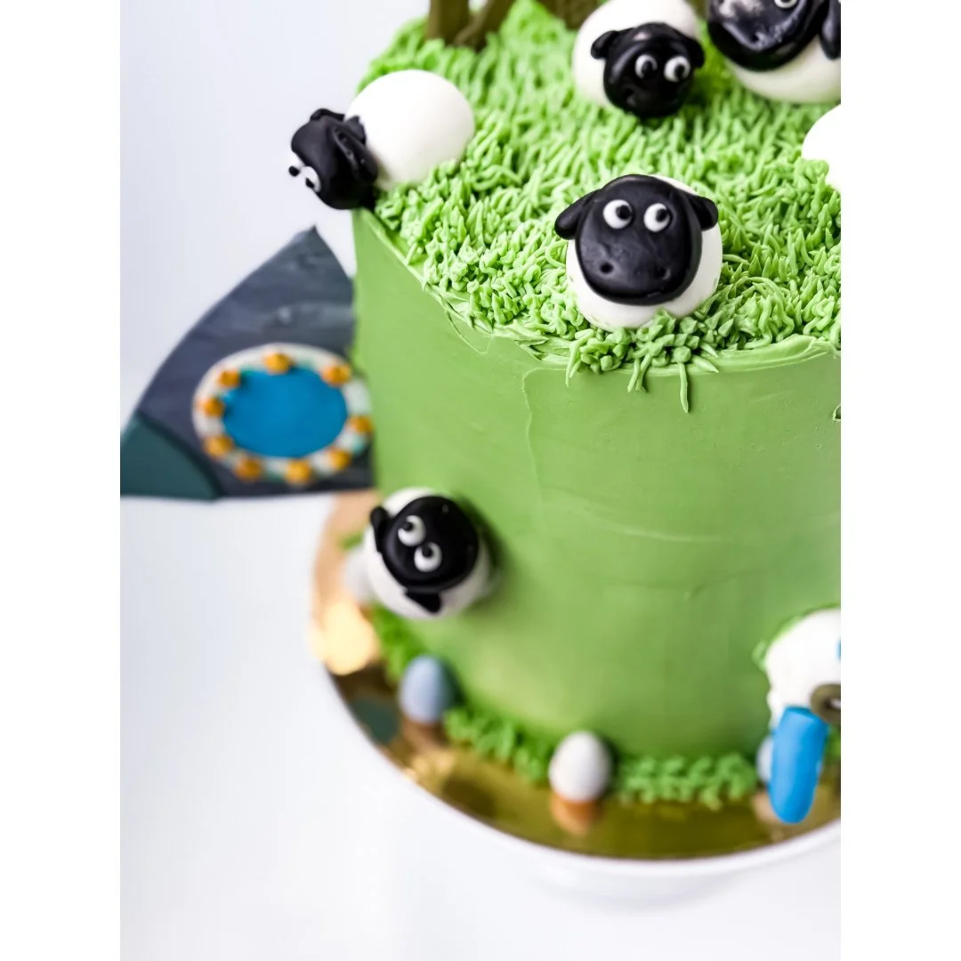 Cake #12 of 2025: Chocolate cake with chocolate frosting designed by my son. This cake includes a spaceship crashing into a field with sheep. There is also a one-eyed alien climbing out of the spaceship. All I can say is that this kid comes up with s