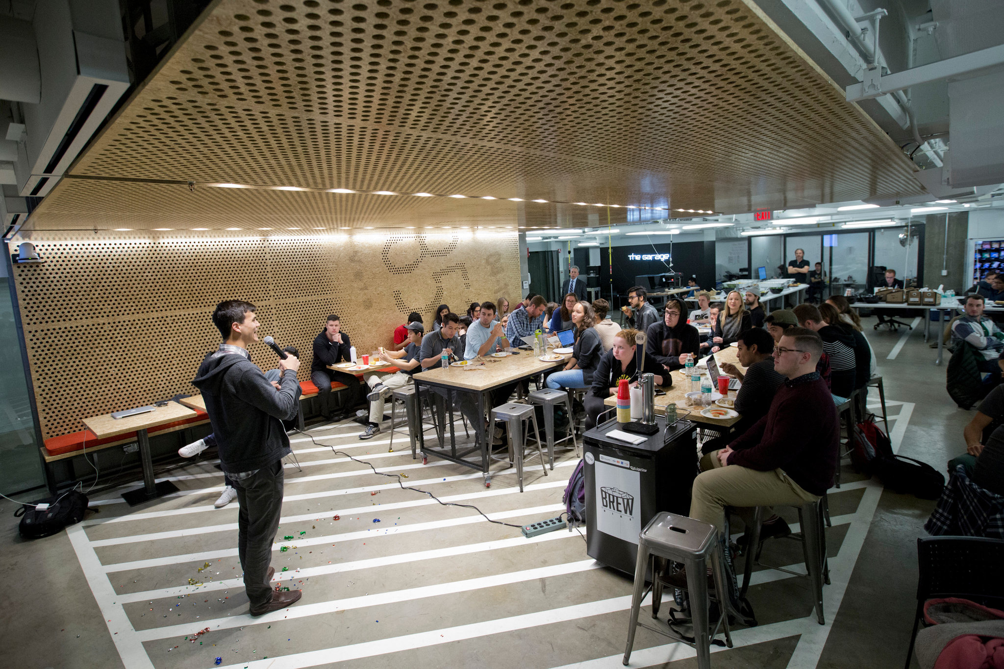 Griffen Kelly, a founder of Trac and a Northwestern alumnus, speaks to students during the weekly dinner at the Garage, which was built in one. Note the parking lines on the floor. CreditNathan Weber for The New York Times
