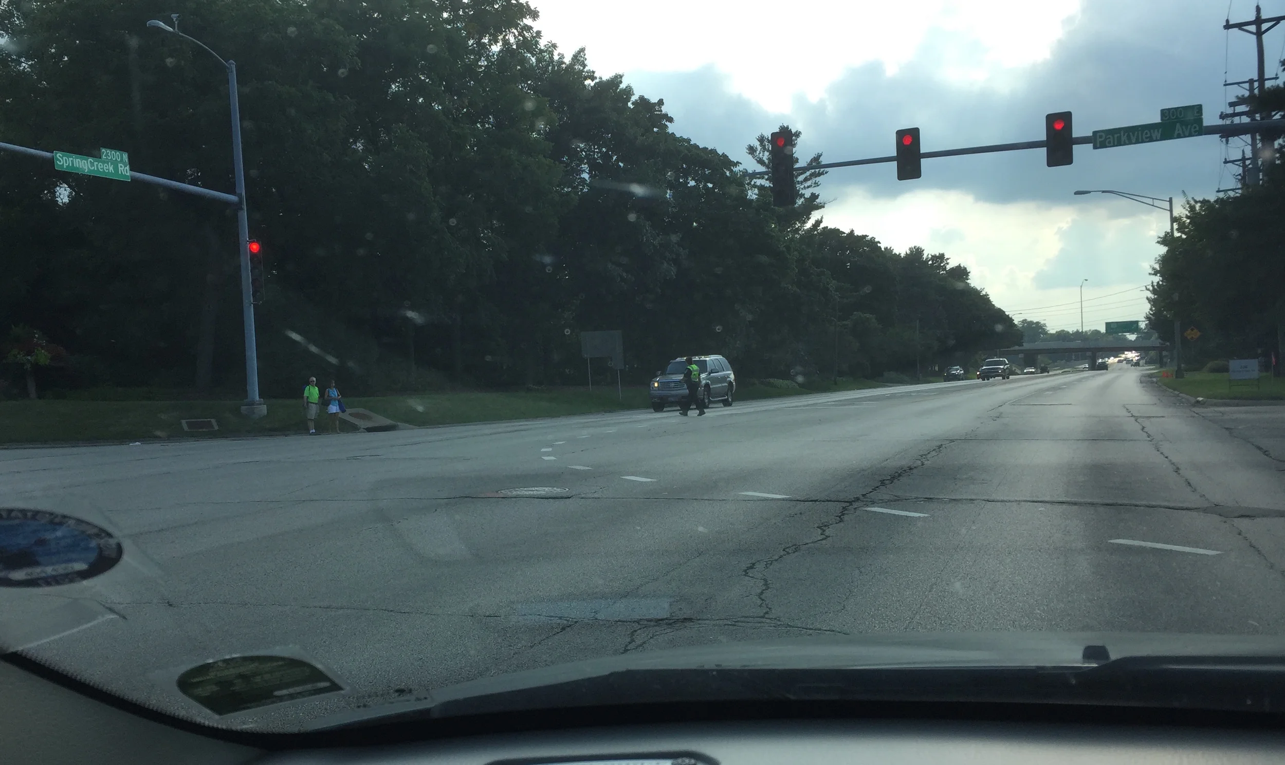 A little hard to see (yes, I was driving. yes, it was a red light), but a police officer crosses 6 lanes to assist two pedestrians waiting to cross to Anderson Gardens on the other side.