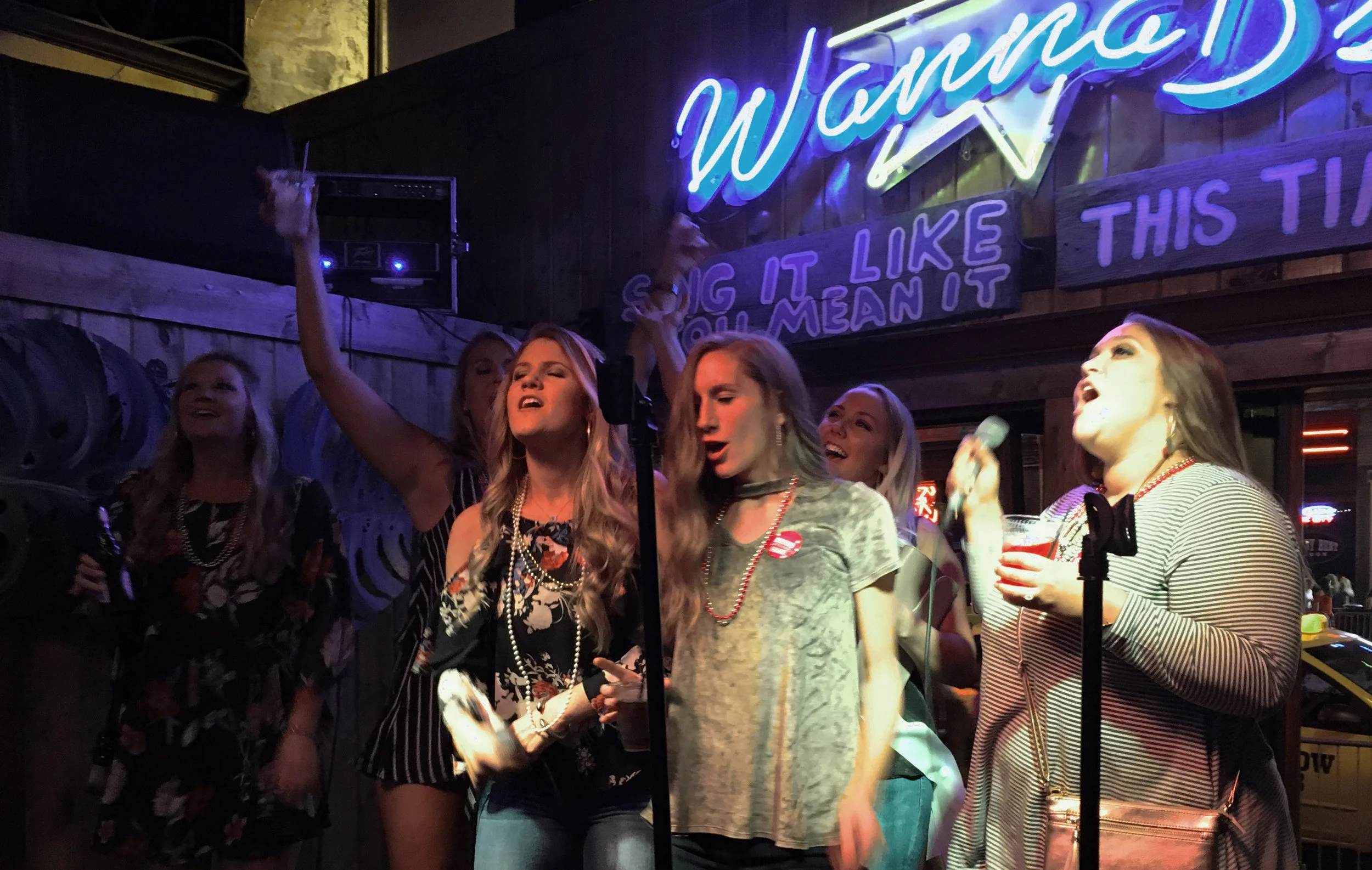 A bachelorette party sings a Carrie Underwood song loud and off-key on the stage at Wanna B's Karaoke Bar on Lower Broadway in Nashville, TN on Thursday, September 27th, 2017. The bride stayed hidden in the background to hide her apparent lack of so…