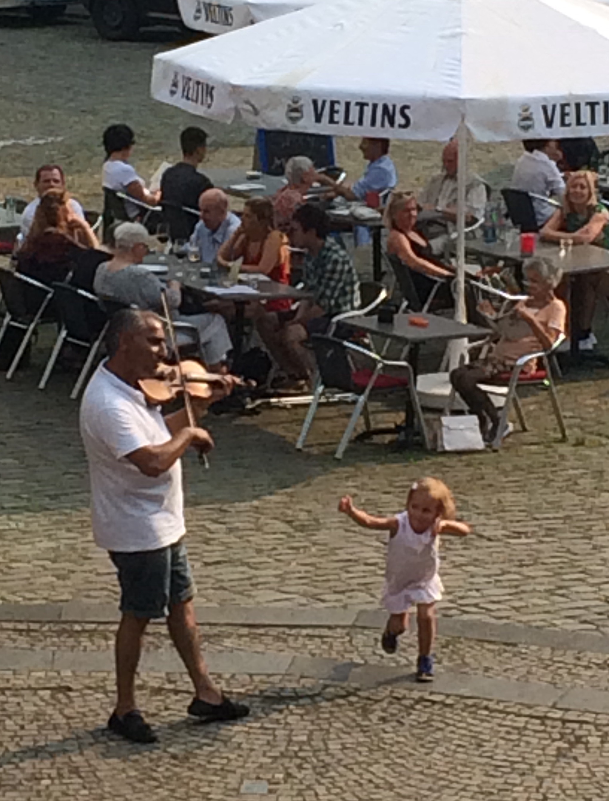 Man playing the violin in Solingen, a child leaps up and dances