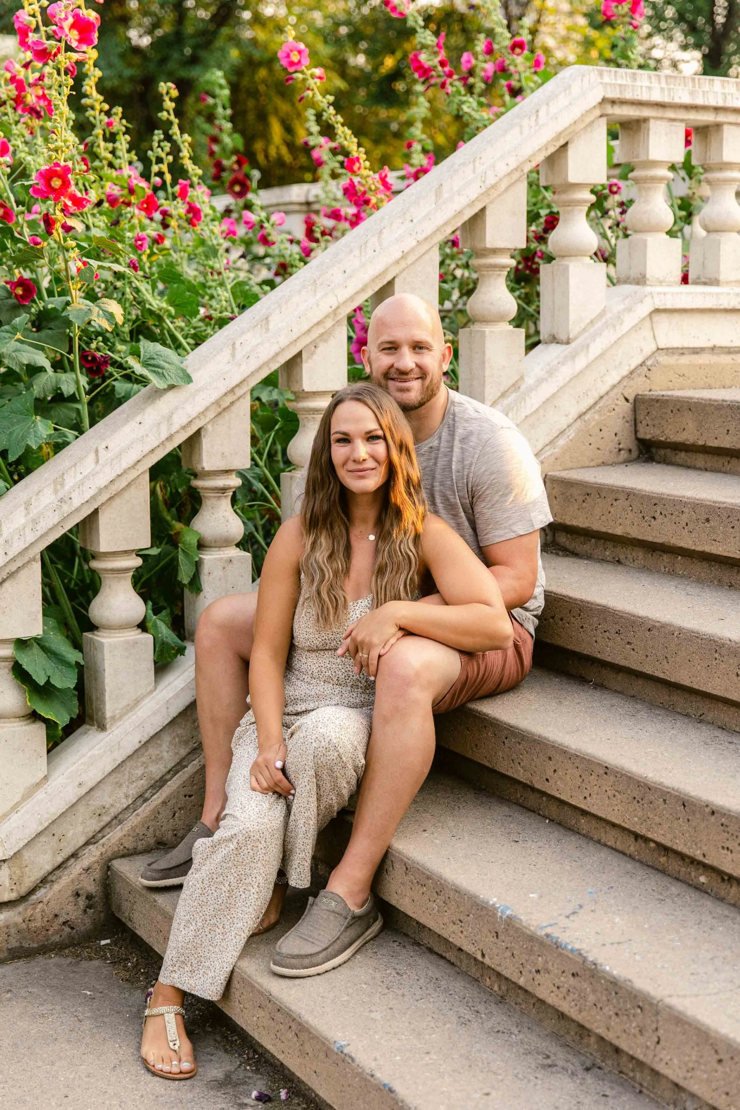A family photo shoot at the Beaulieu Gardens at Lougheed House, sitting on the terrace stairs that are classically designed with pink hollyhocks in the background