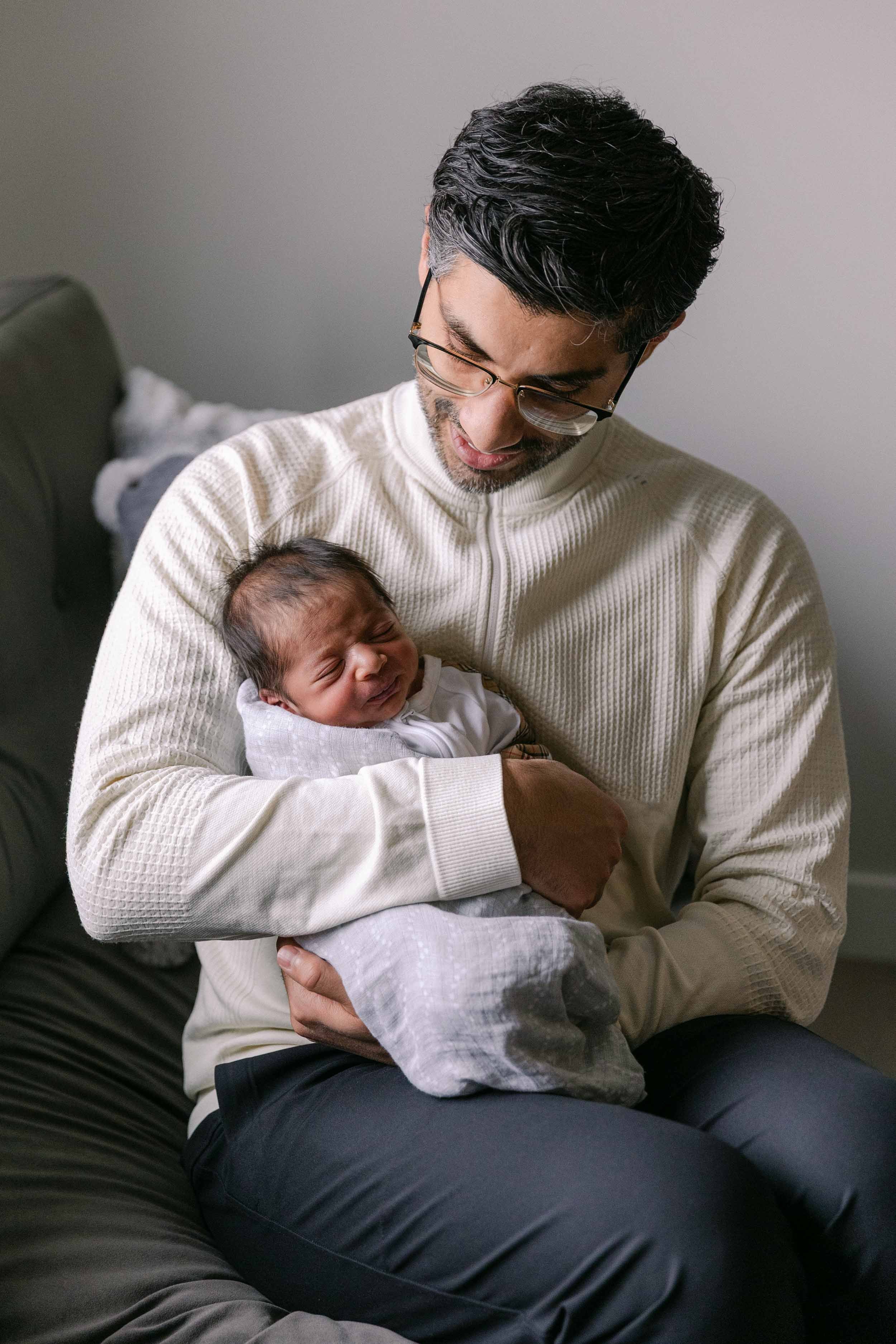 Father and baby newborn lifestyle shoot, wearing cream, white and black neutrals, indian father and son
