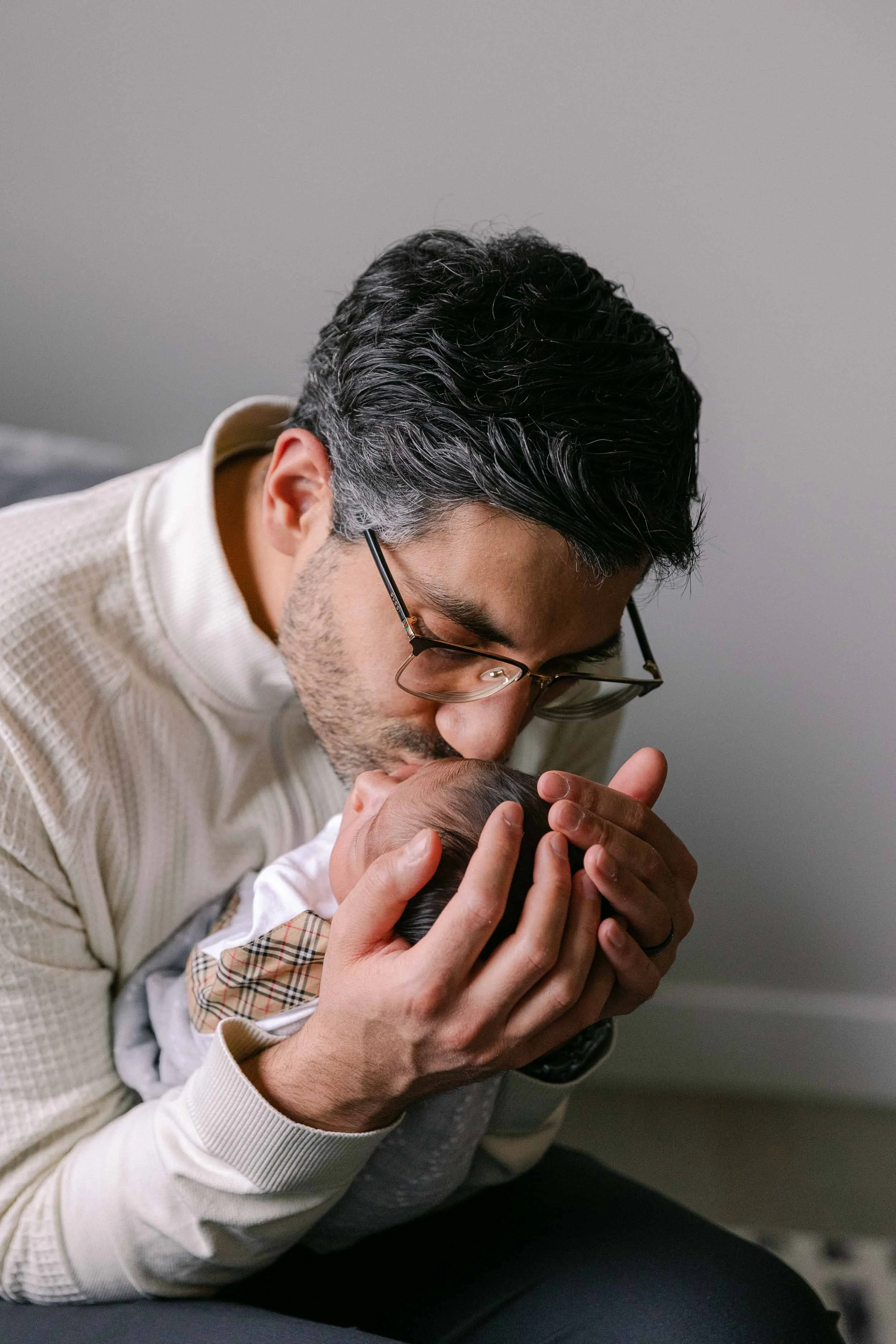 Father and baby newborn lifestyle shoot, wearing cream, white and black neutrals, indian father and son