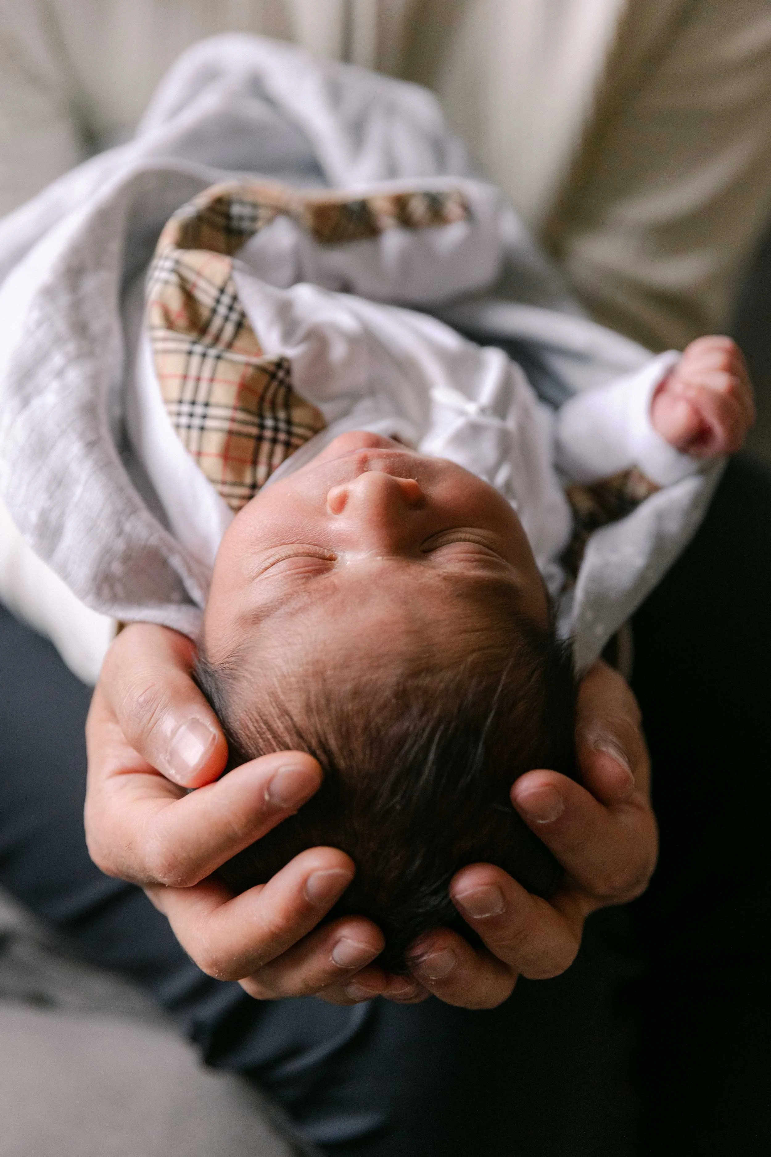 Father and baby newborn lifestyle shoot, wearing cream, white and black neutrals, indian father and son, holding his head in his hands
