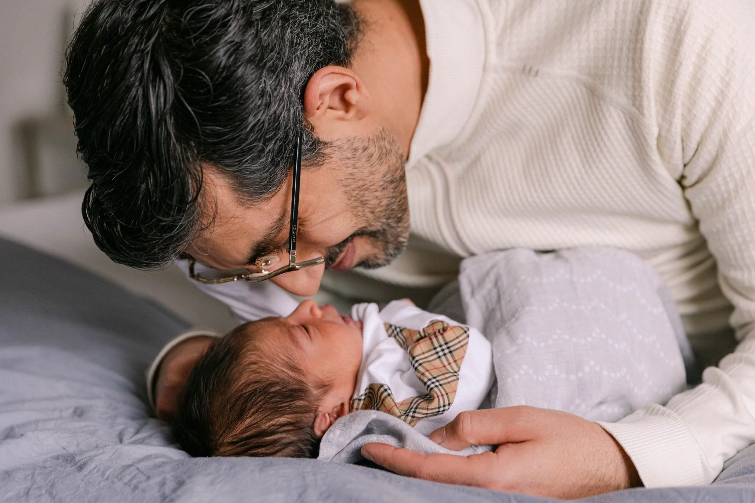 father nose to nose with baby, newborn lifestyle shoot, wearing cream, white and black neutrals, indian father and son