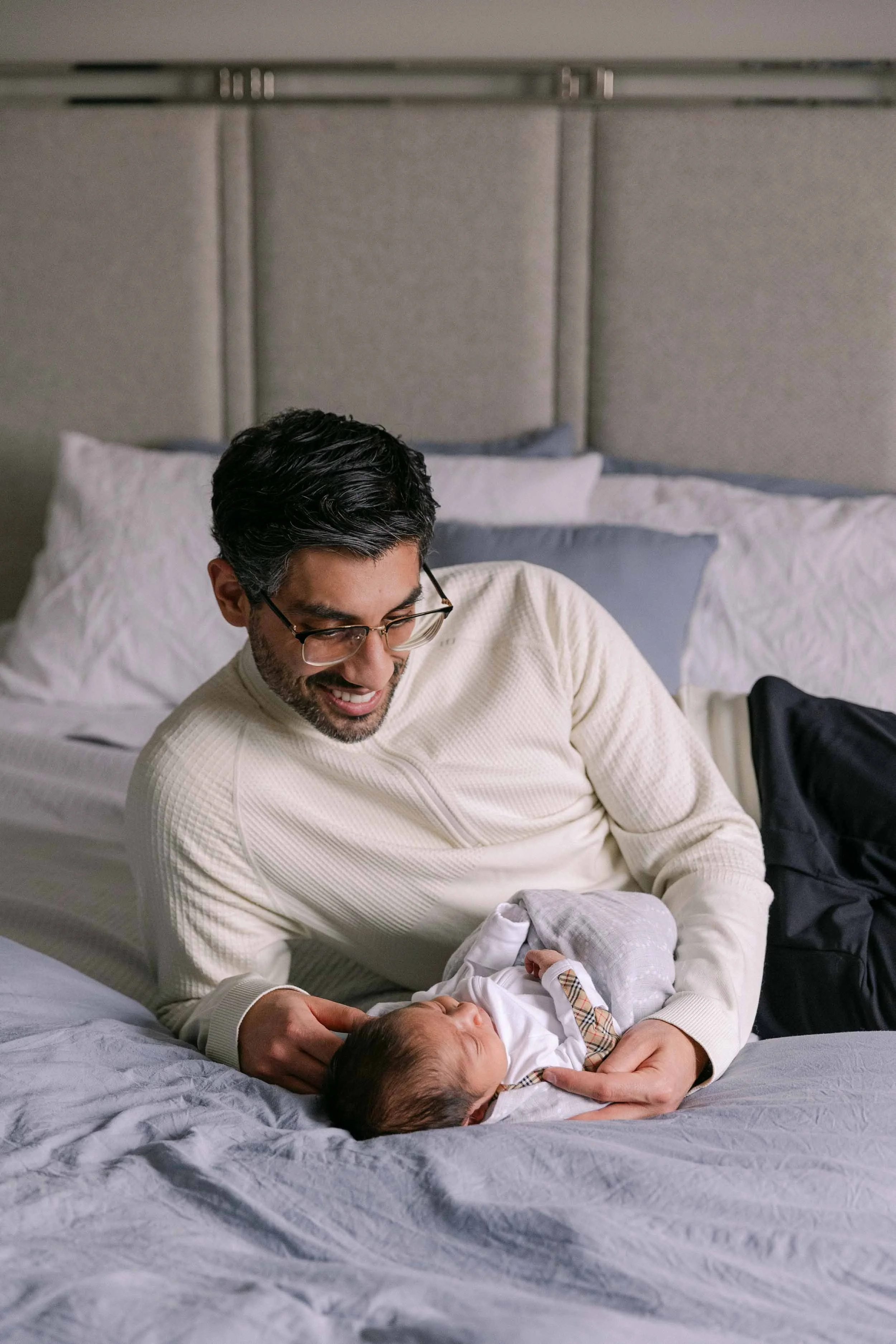 dad and baby on bed, newborn lifestyle shoot, wearing cream, white and black neutrals, indian father and son