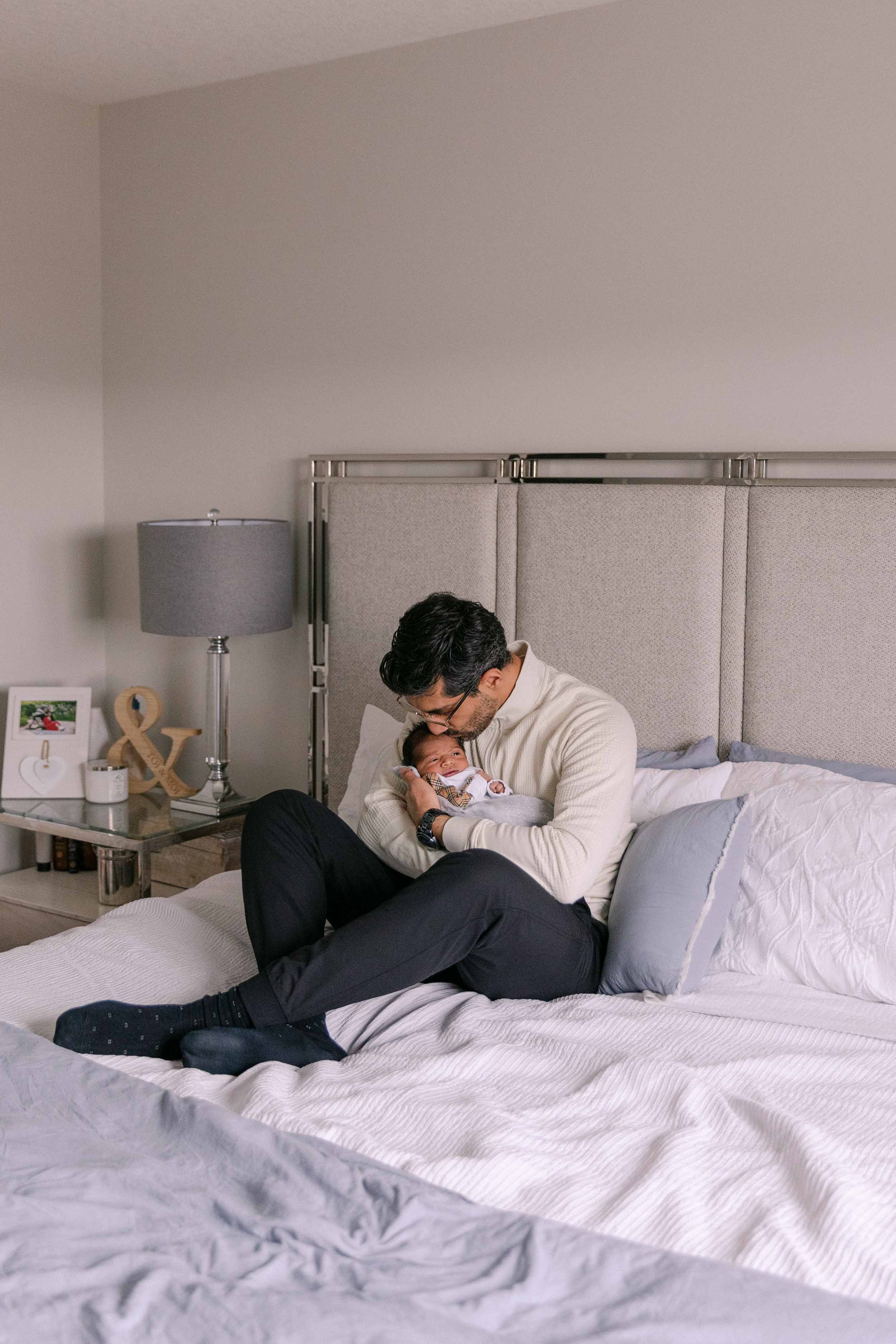 dad and baby on bed, newborn lifestyle shoot, wearing cream, white and black neutrals, indian father and son