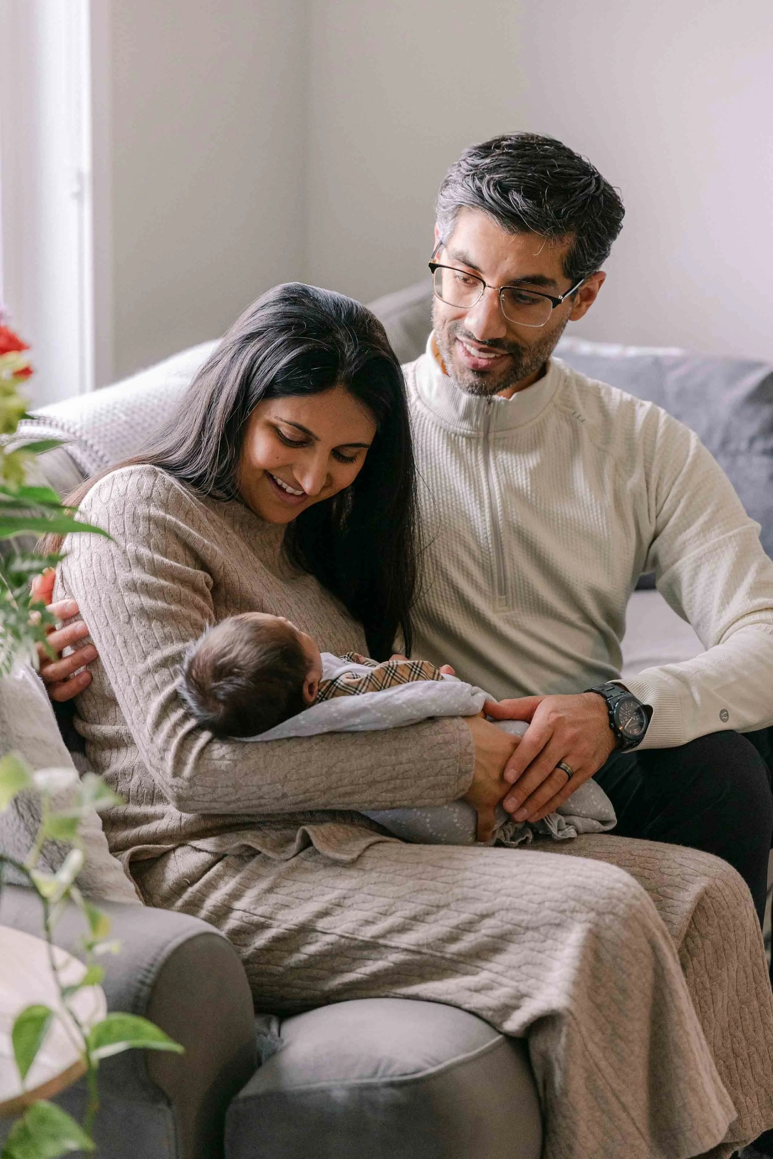 mom, dad and baby on couch, newborn lifestyle shoot, wearing cream, white and black neutrals, indian mother, father and son
