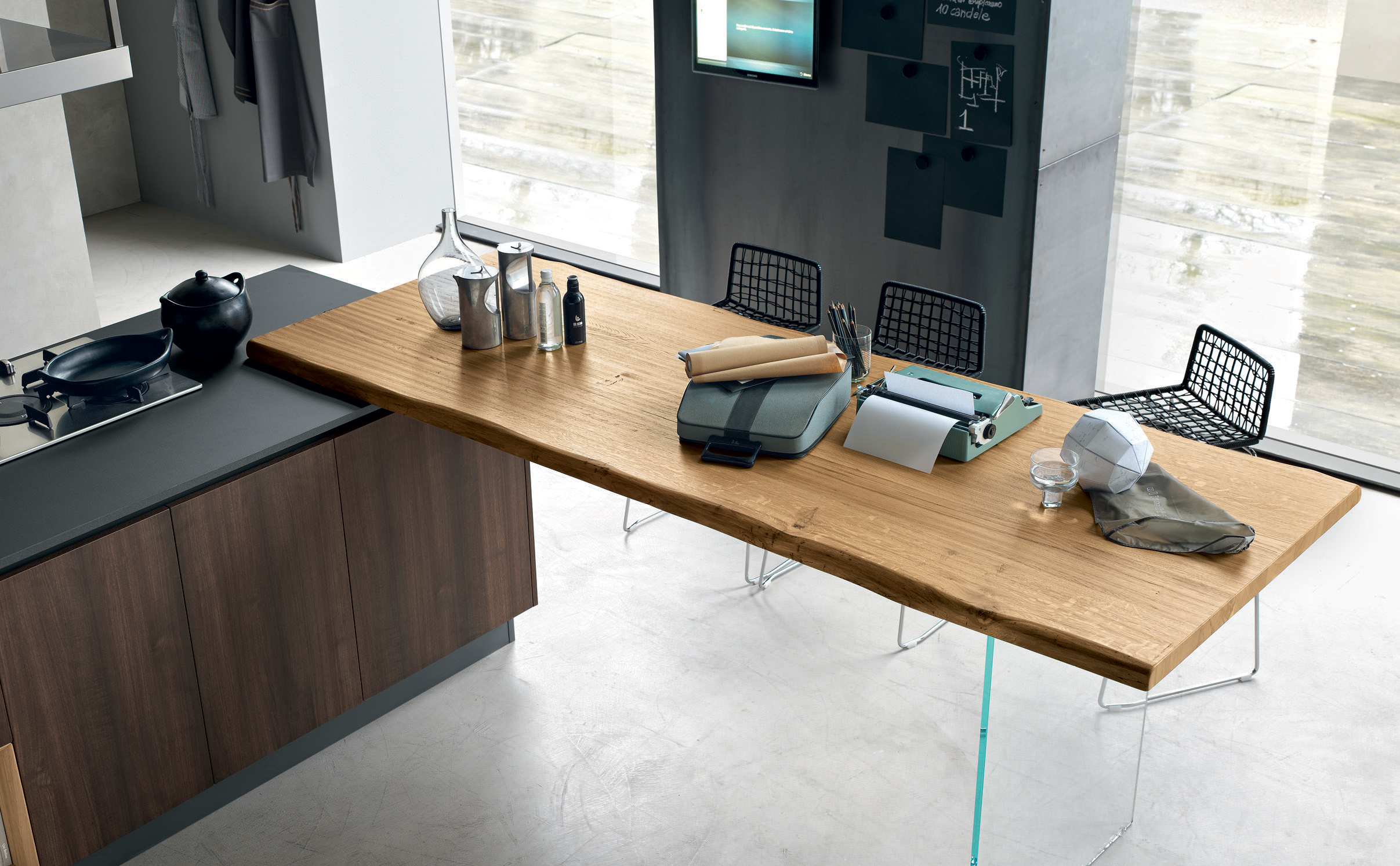  In a natural versions, the wood characterizes the counter and plays with the overlap. It creates a furnishing harmony throughout the composition, which is brought out even more by the elegance of the adjustable glass table leg.&nbsp;&nbsp; 