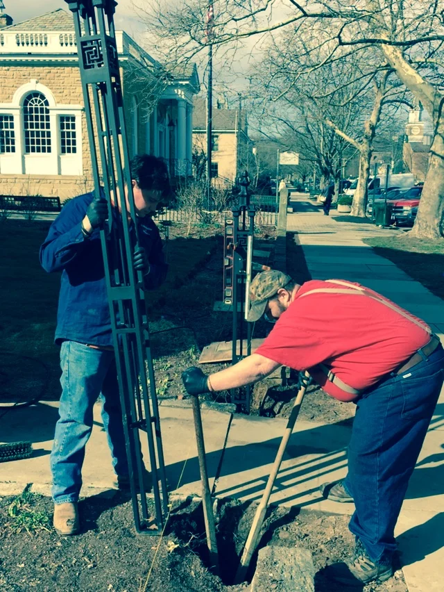 James Sayre and Brendan Kennedy, employees of Eagle Machine and Welding, set the gate post for the new fence.