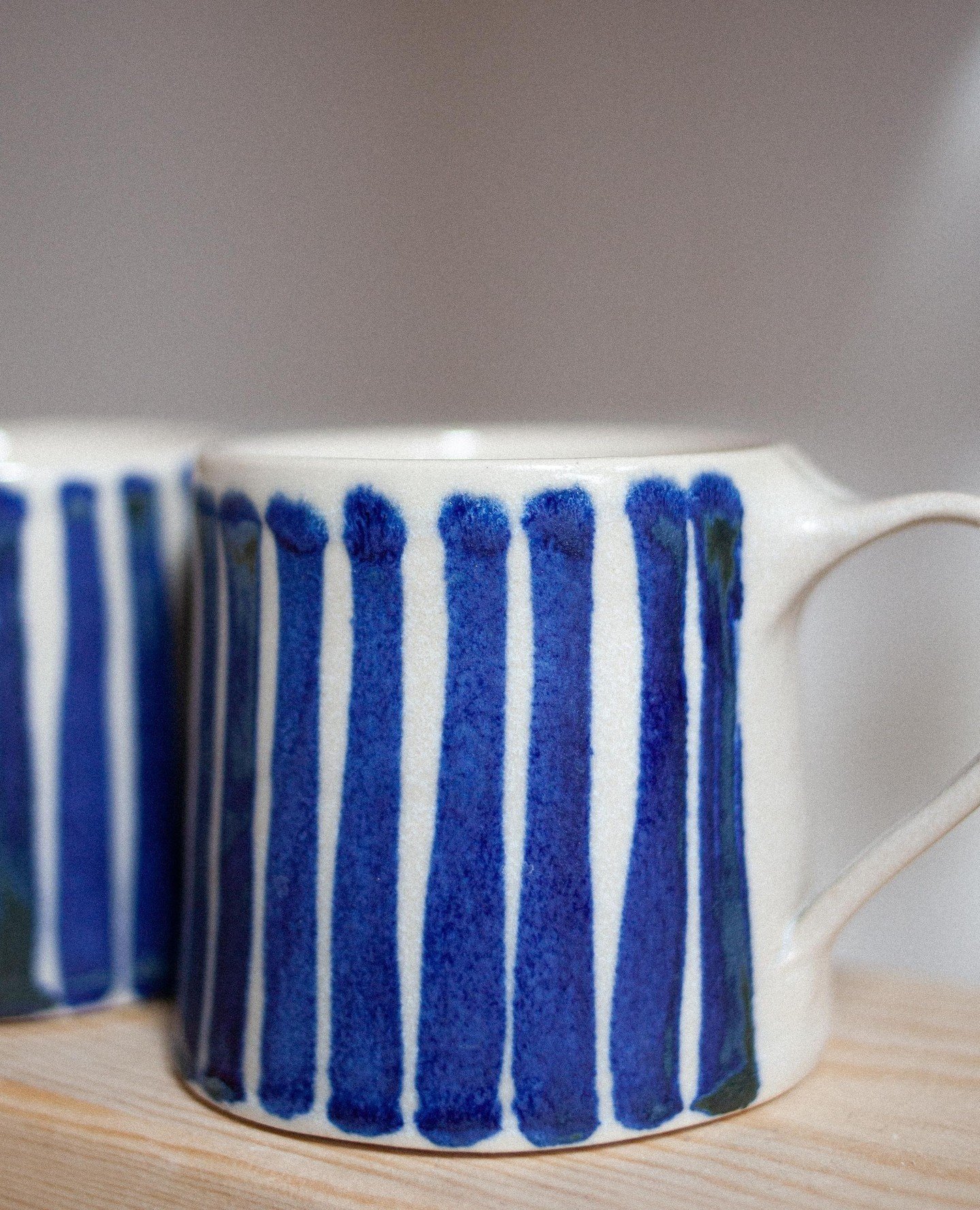 A wheel-thrown tall mug, with a high-gloss interior and rim, a variegated matte white exterior and hand-painted blue stripes in my classic cobalt wash design. So looking forward to sharing these new Summer blues with you soon.⁠
⁠
Cobalt update coming