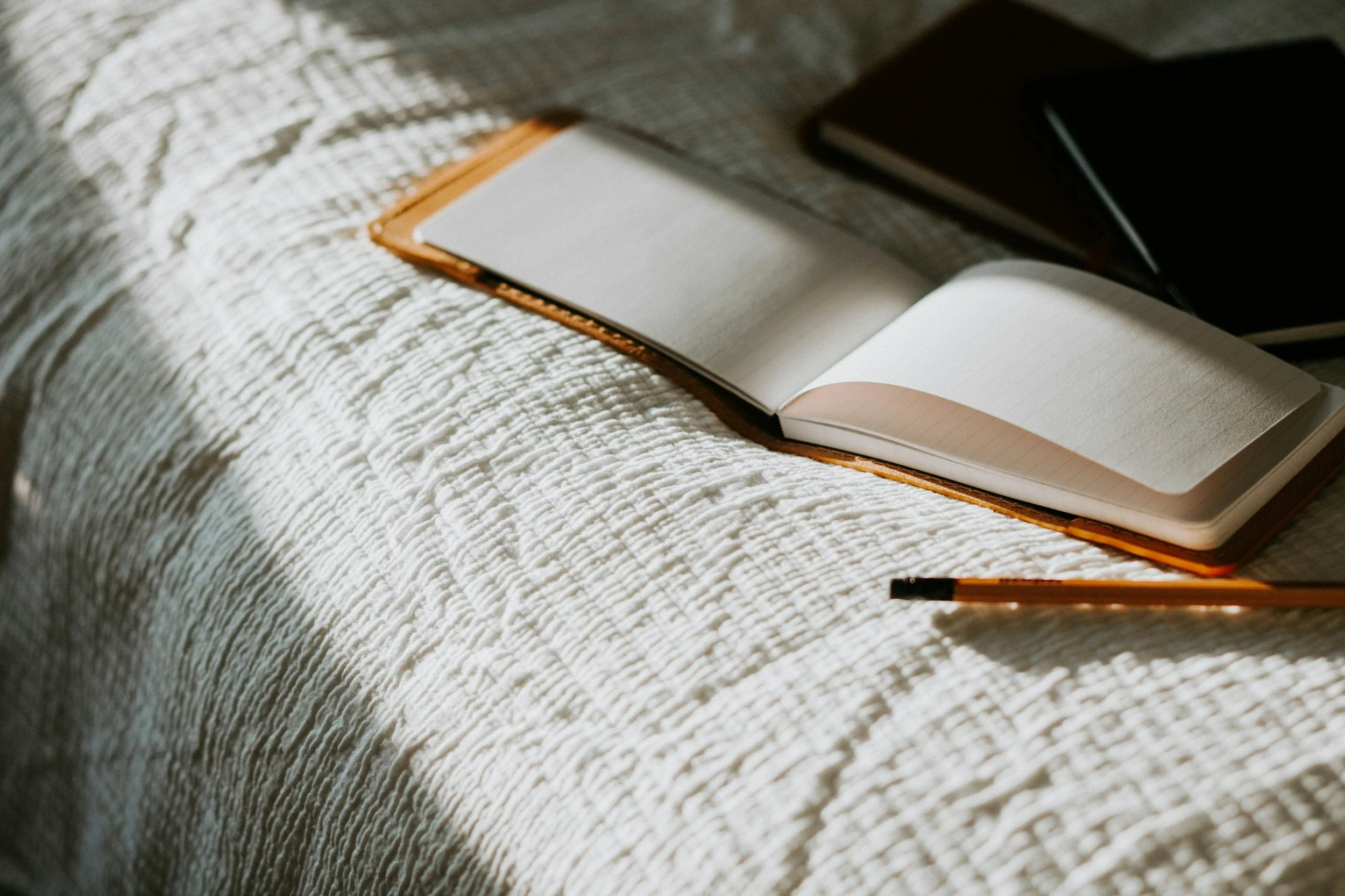 Image of a bed, with journals and pencil