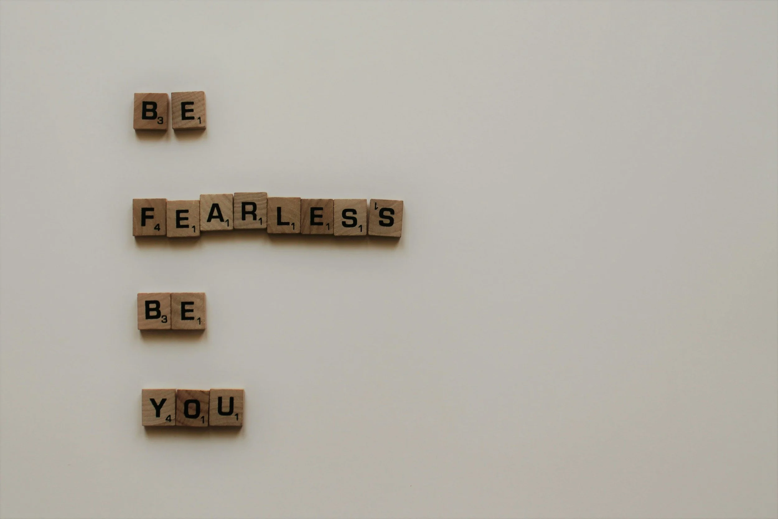 Scrabble letters spelling out be fearless be you on a white background