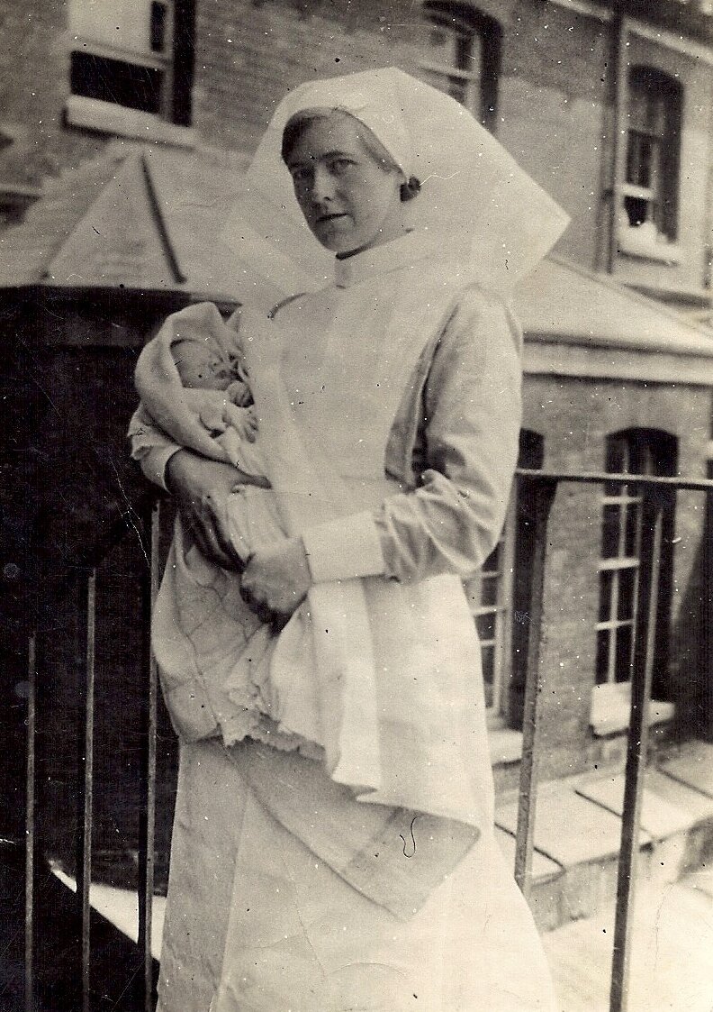 Midwife Lucy Ford Carrying a Newborn Baby.