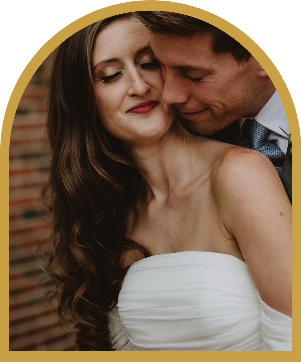 Bride and groom embracing in a close-up wedding portrait, framed by a gold arch.