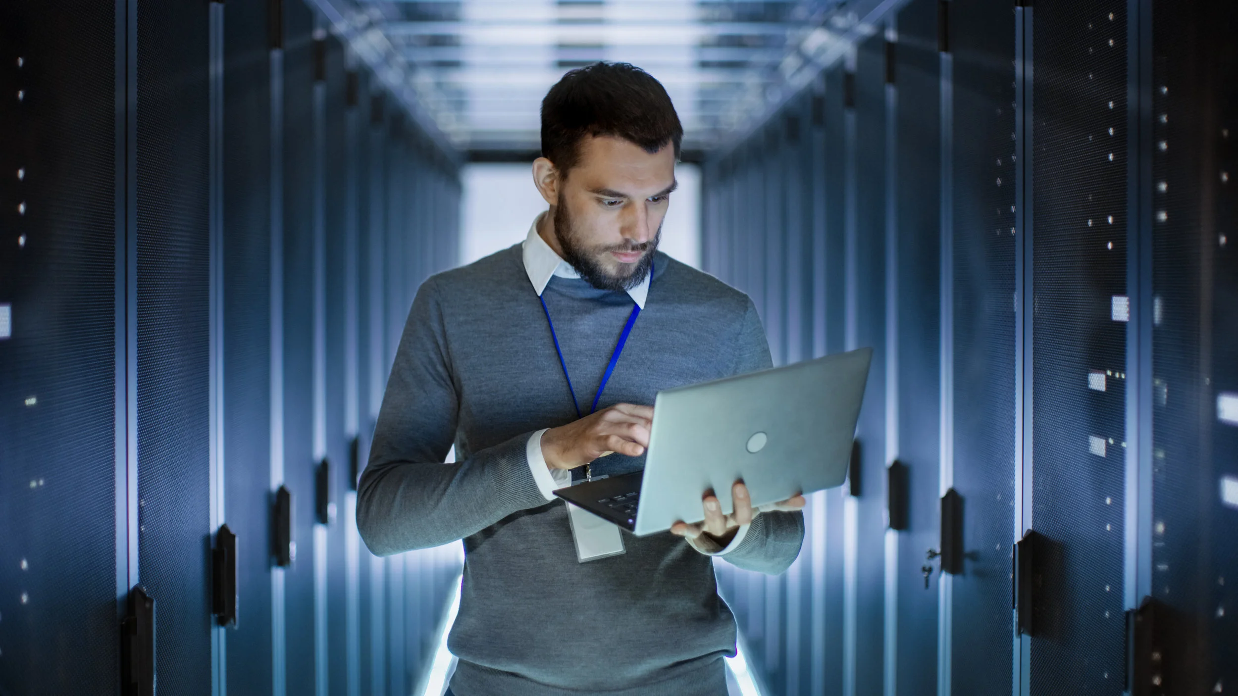 Canva - Male Server Engineer Works on a Laptop in Large Data Center..jpg