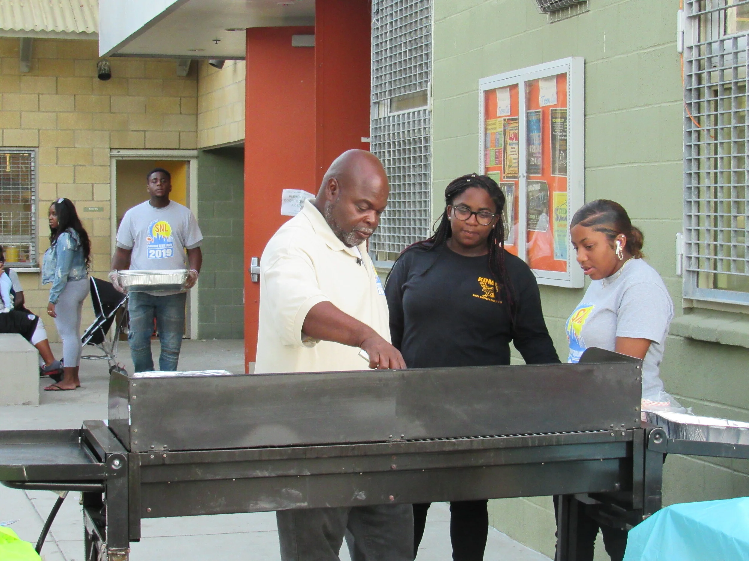 Larry managing the grill with neighborhood youth.