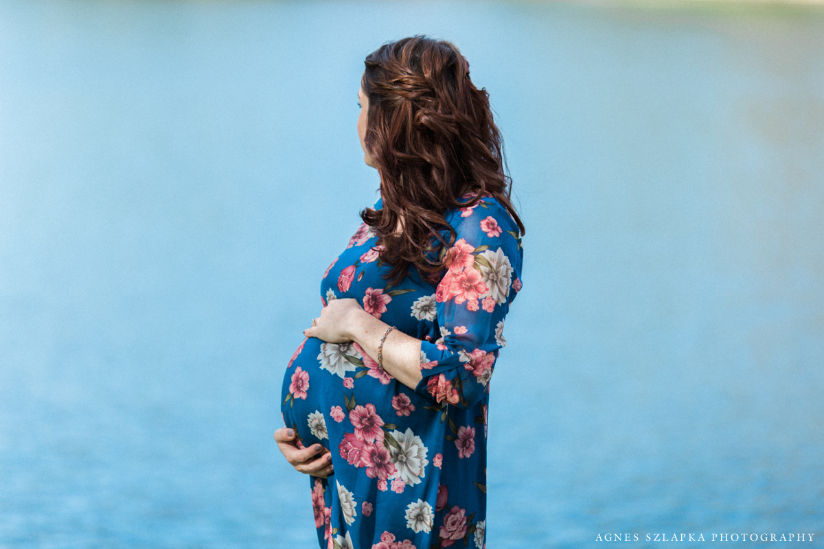 pregnant woman looking at lake holding belly | cleveland, ohio maternity photographer