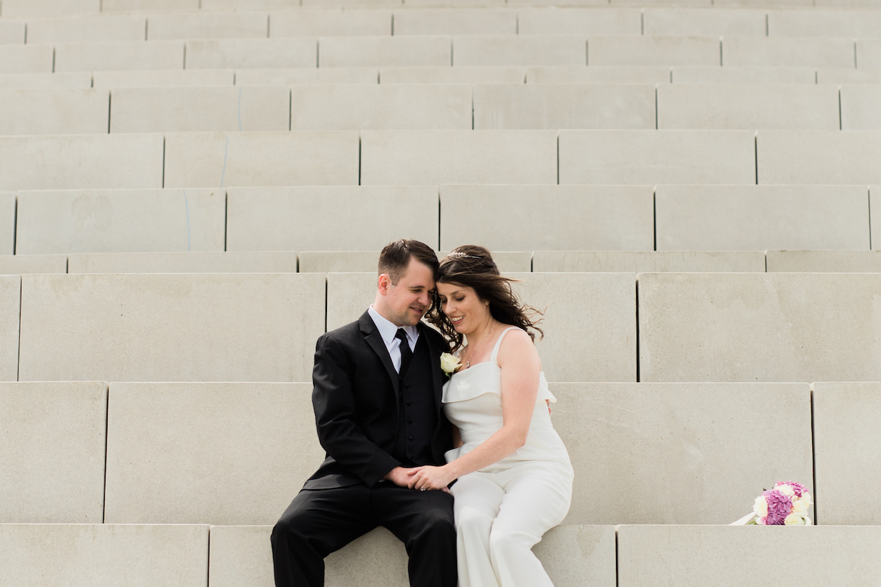 husband and wife sitting on solstice steps in lakewood park | cleveland wedding portraits