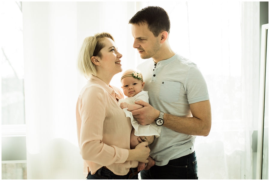 mom and dad in front of window with infant daughter | cleveland, OH newborn photographer 