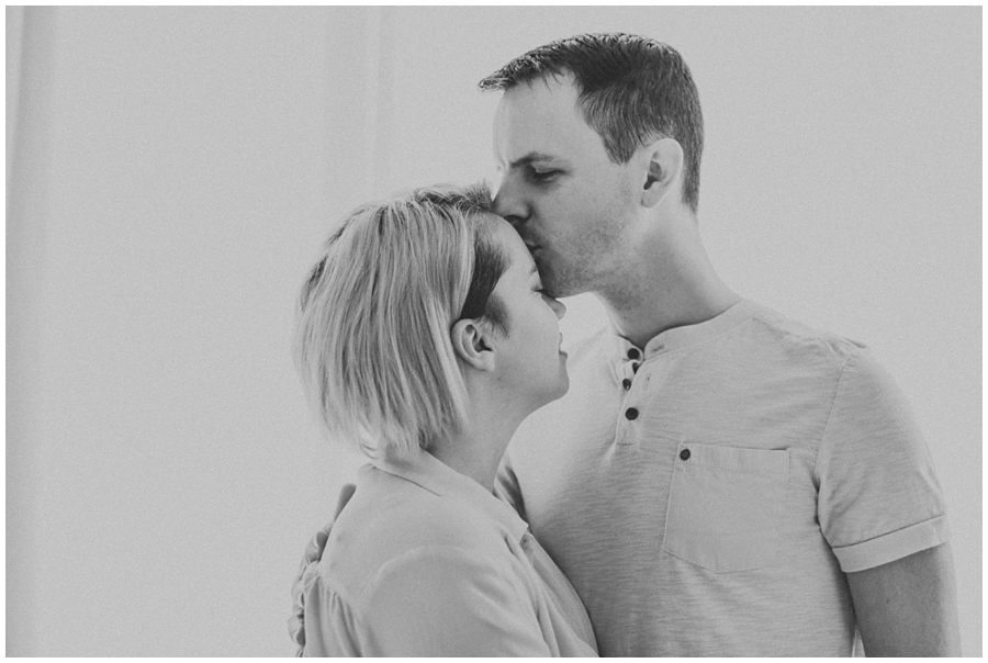 dad kissing mom on forehead in bedroom | cleveland, OH newborn photography