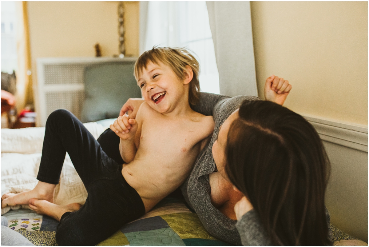 mom and oldest child laughing on bed | cleveland, OH newborn photography