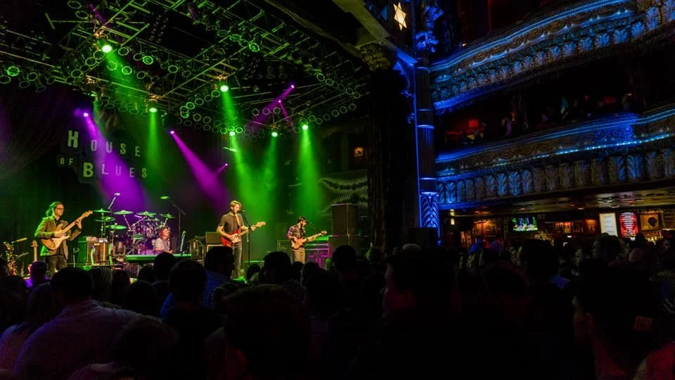 A concert featuring a band on stage with dramatic lighting.