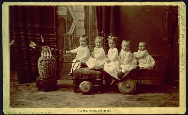 Five Small Children Seated on Vehicle with the Child in the Front Holding a Small US Flag | Circa 1891