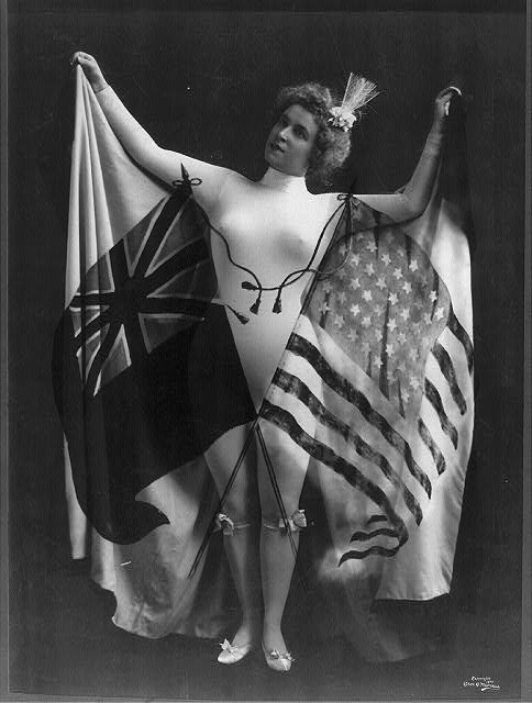 Woman in White Body Suit Holding Spread Cap with Superimposed US and British Flags | Circa 1899