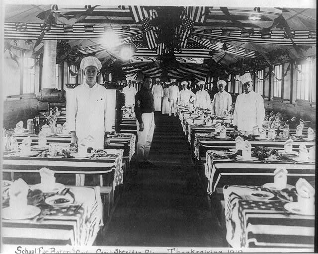 School for Bakers and Cooks, Camp Sheridan, Alabama with Tables and Ceiling Decorated with Flags | Circa 1918