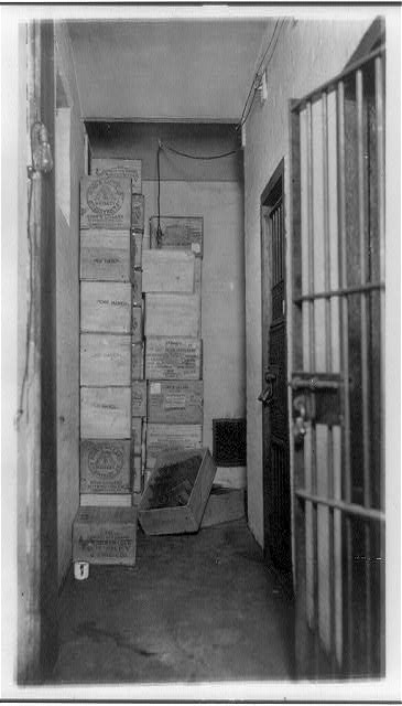 Cases of Confiscated Liquor Stacked in Corner of Room with Barred Doors | Circa 1921