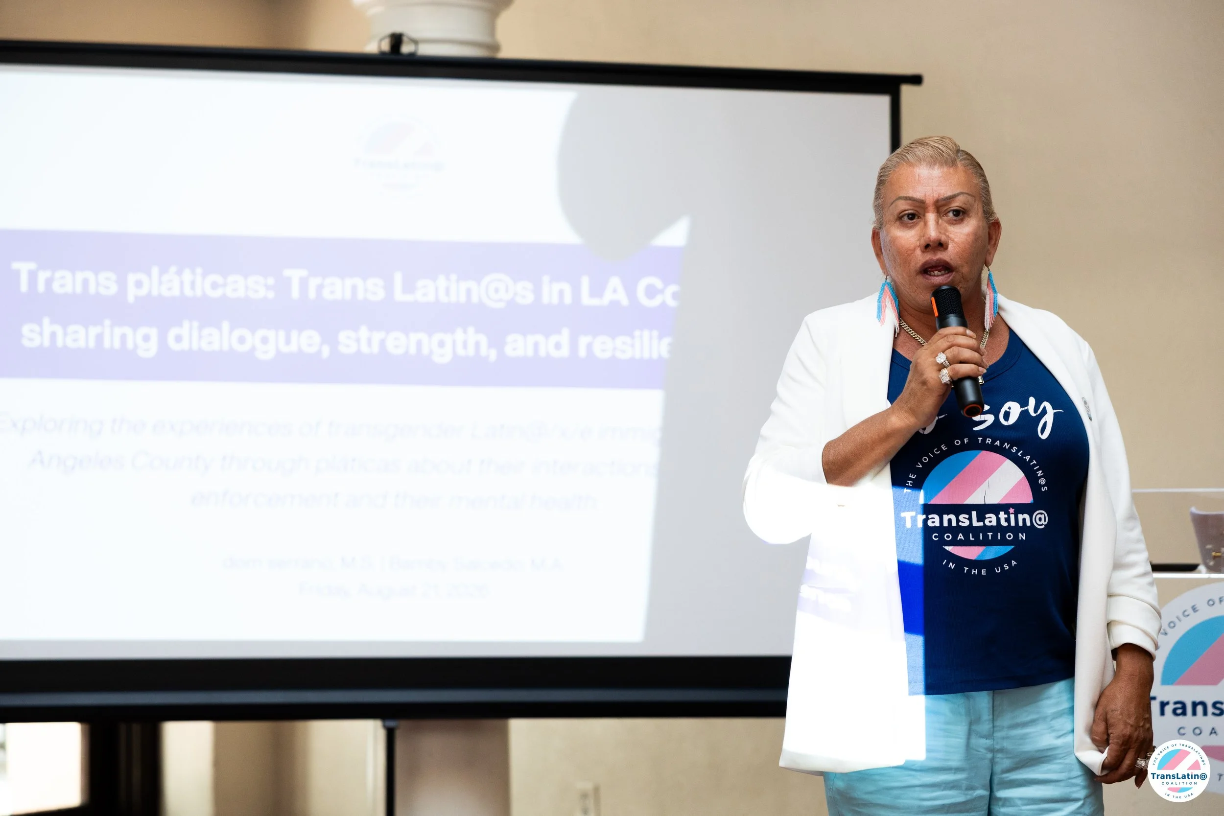 Bamby Salcedo speaks into a microphone during the Trans Pláticas report release event.
