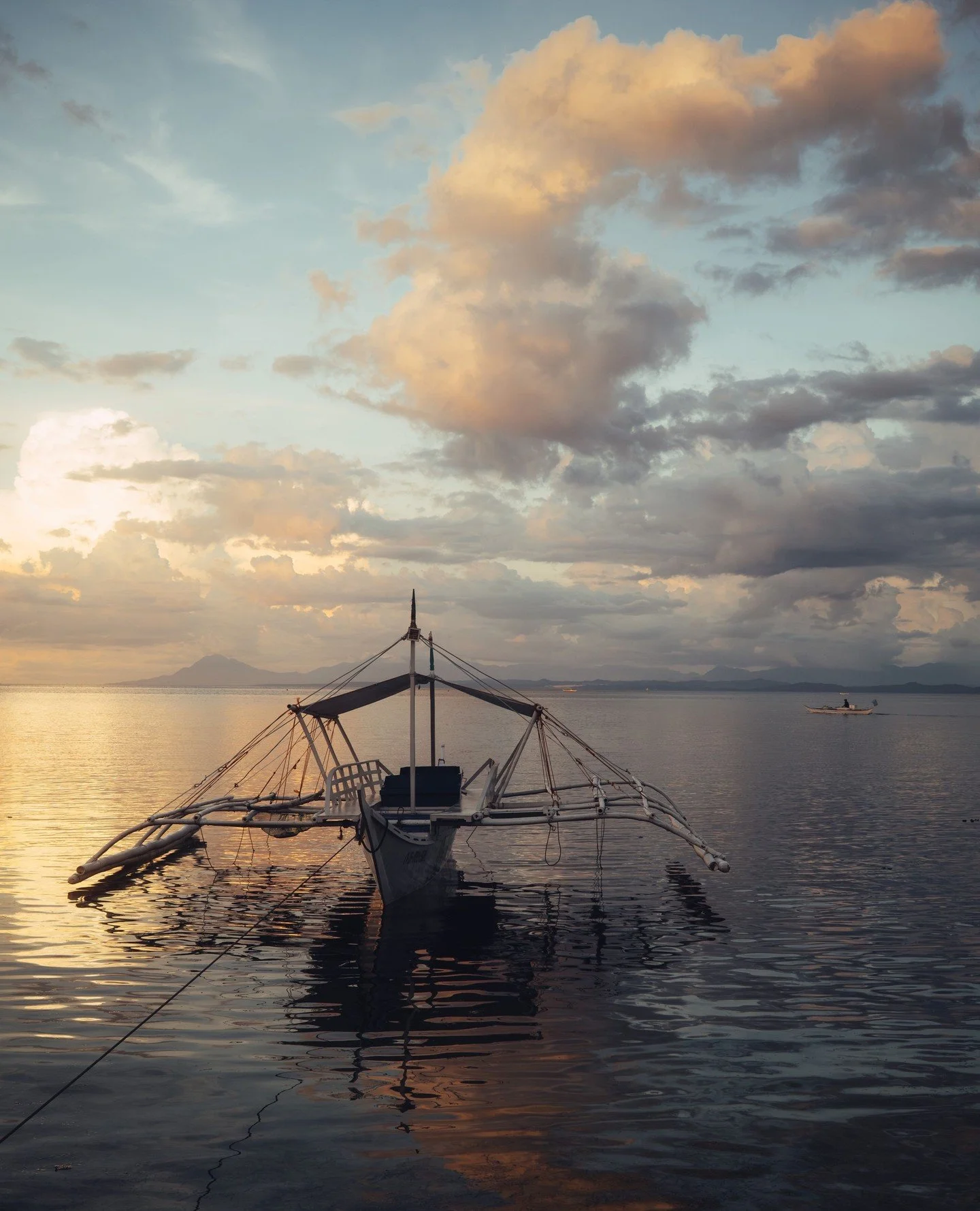 First light spills softly over the palms.⁠
The air is warm already, but still. No engines. No voices. Just the slow rhythm of small waves folding into white sand.⁠
Roosters somewhere inland. A banca rocking gently against its rope.⁠
The ocean looks f