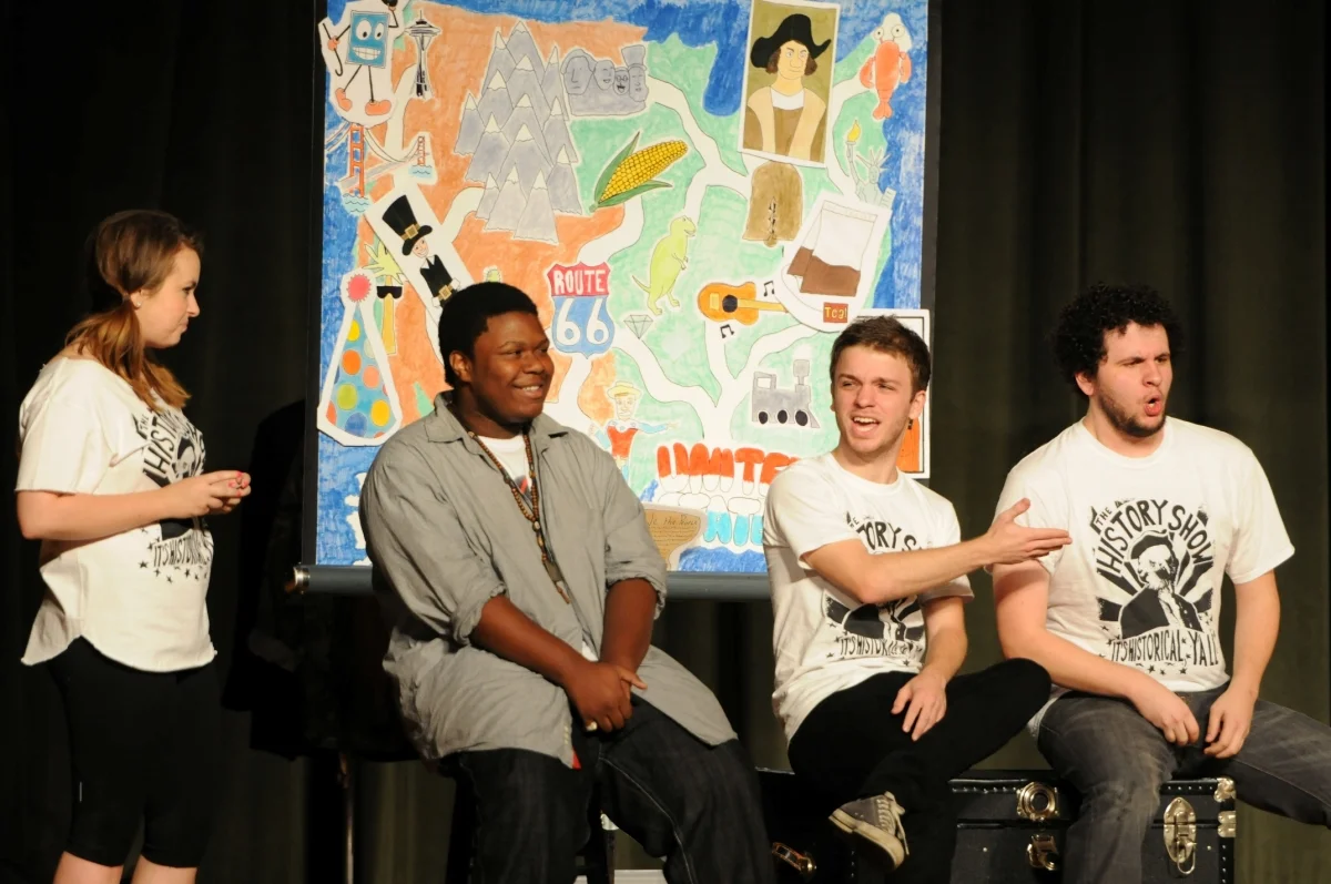Sarah Jane Robinson, Quinn Gassaway, and Asa Tims interact with a high school student as they perform The History Show (2012).