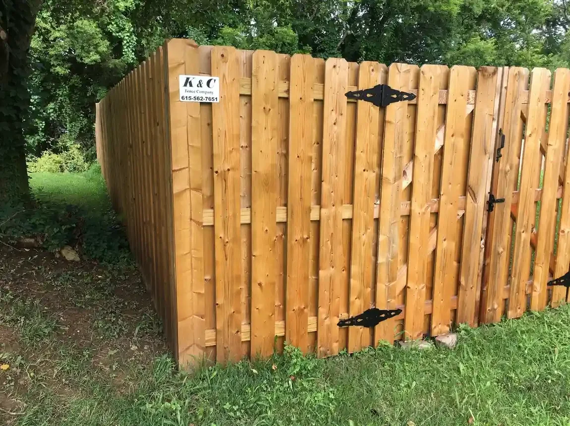 K&C Fence shadowbox cedar privacy fence with a wood gate in a leafy Nashville, Tennessee yard.