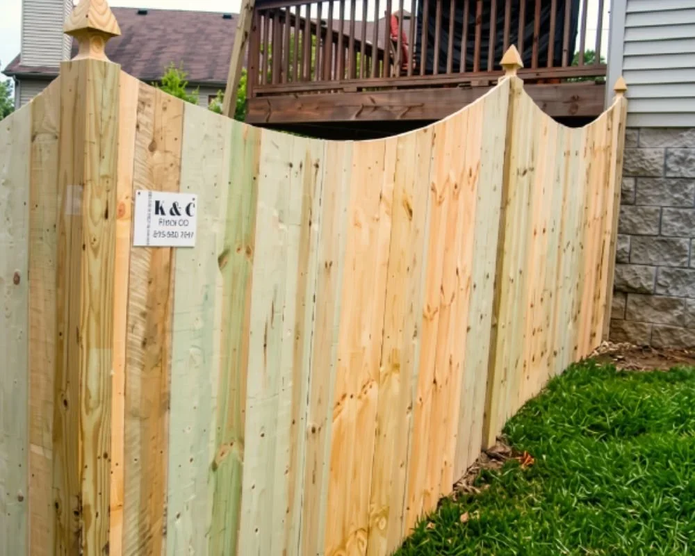 K&C Fence concave wood privacy fence with decorative post caps beside a backyard deck in Nashville, Tennessee.
