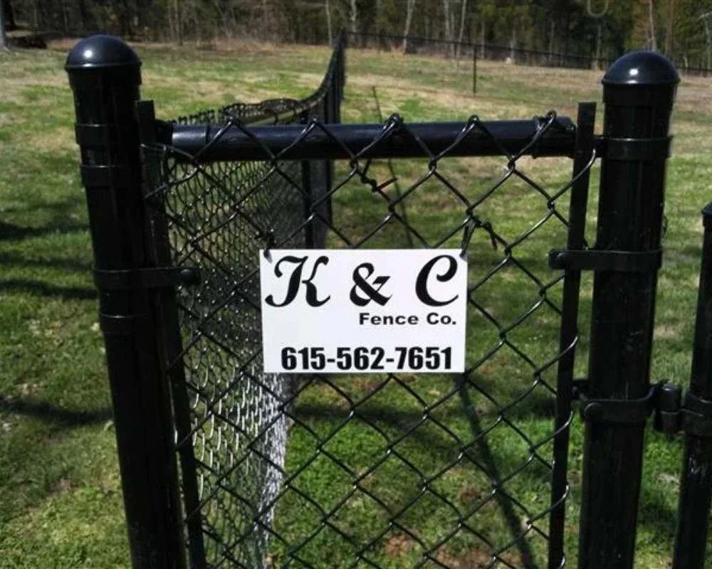 K&C Fence black vinyl chain-link gate enclosing a grassy property in Nashville, Tennessee.