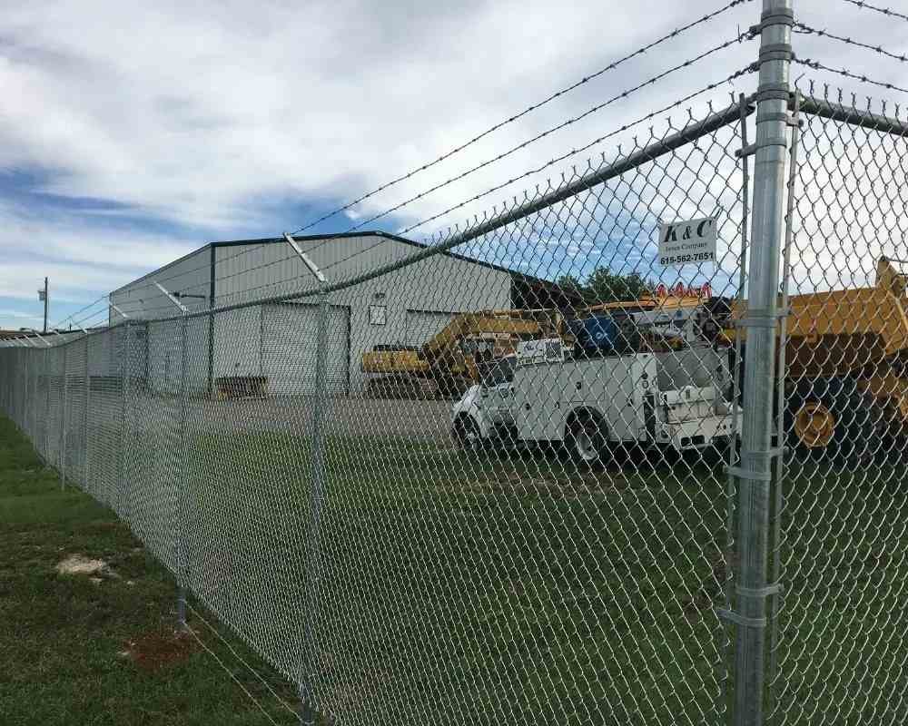 K&C Fence galvanized chain-link security fence with barbed wire around an industrial yard in Nashville, Tennessee.