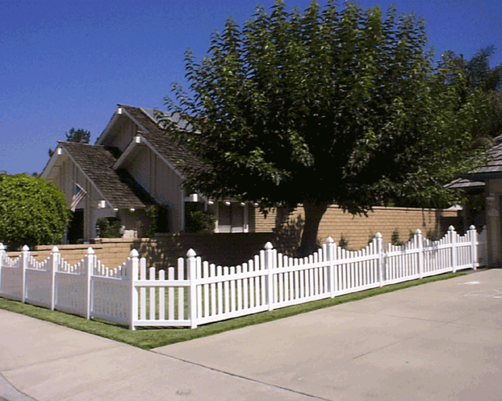 A white vinyl picket fence installed along a residential front yard, adding classic curb appeal and clear boundaries by K&C Fence.