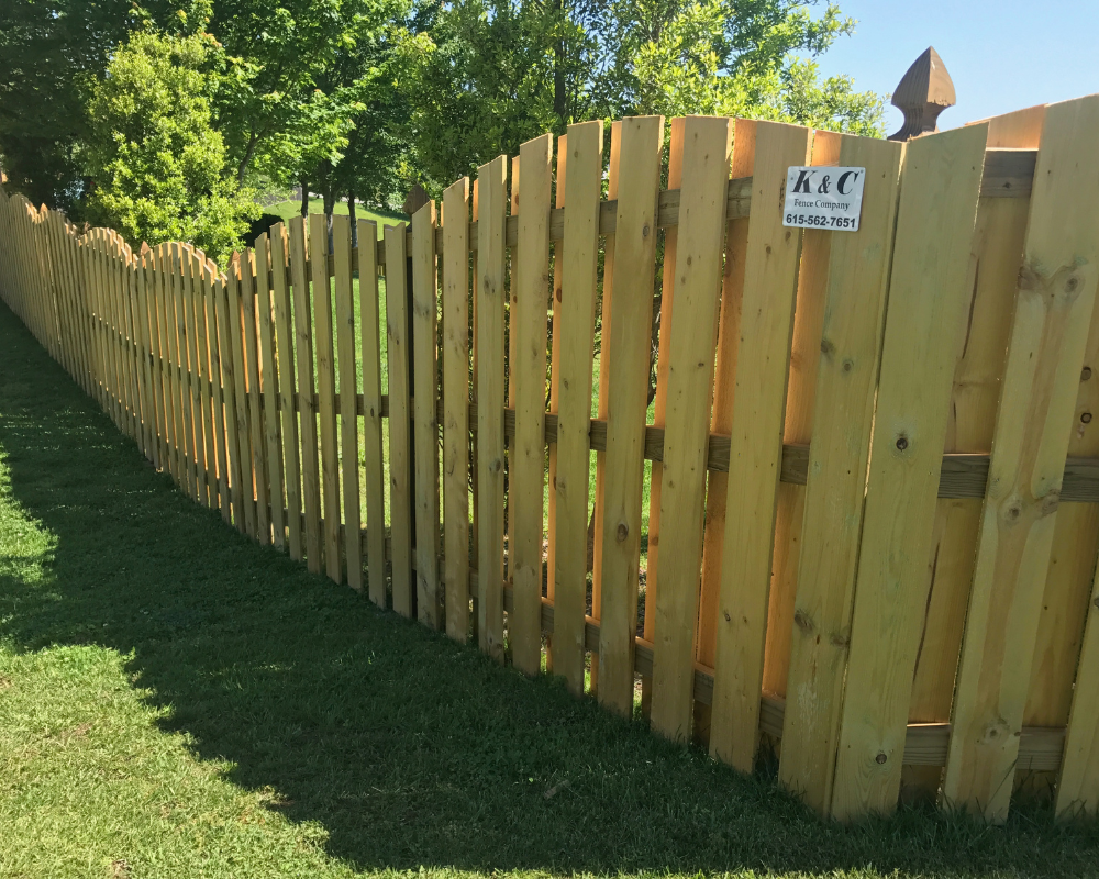 A wood shadowbox fence with alternating vertical pickets running along a grassy backyard, installed by K&C Fence in Murfreesboro, Tennessee.