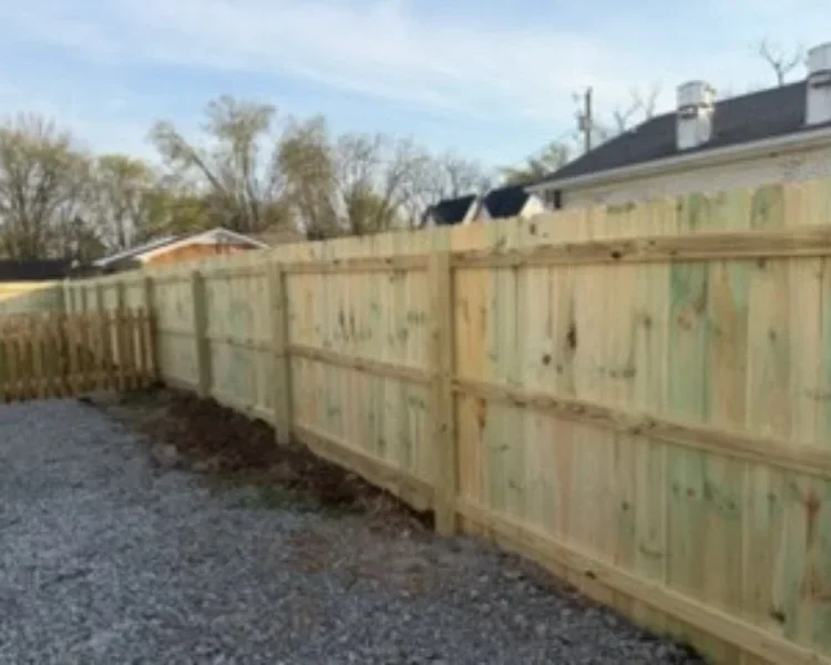 A newly installed wood privacy fence by K&C Fence runs along a gravel driveway, creating a secure backyard boundary at a residential property in Brentwood, Tennessee.