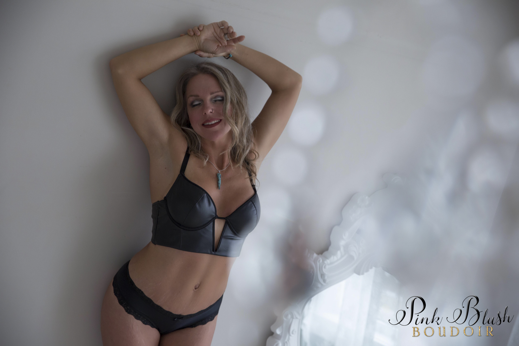 boudoir photos a woman in a black bra and panty set against a wall