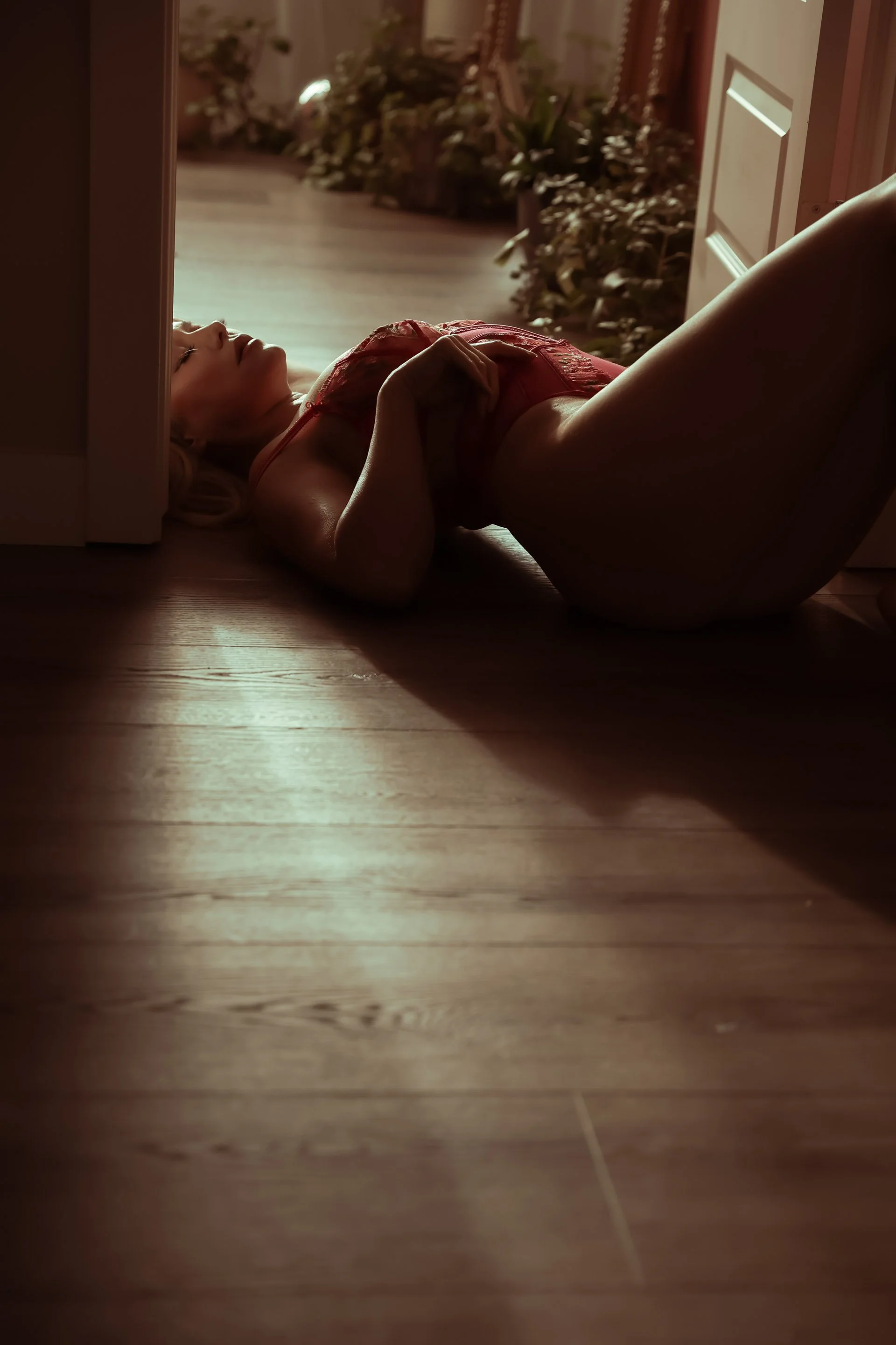 Woman laying on floor in sunlight, pink bodysuit, Edmonton boudoir studio