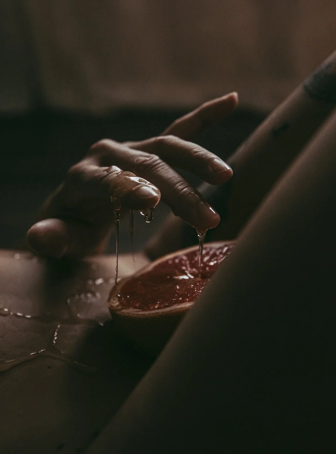 Close-up of a hand dripping juice from a grapefruit half, in luxury boudoir studio Edmonton.