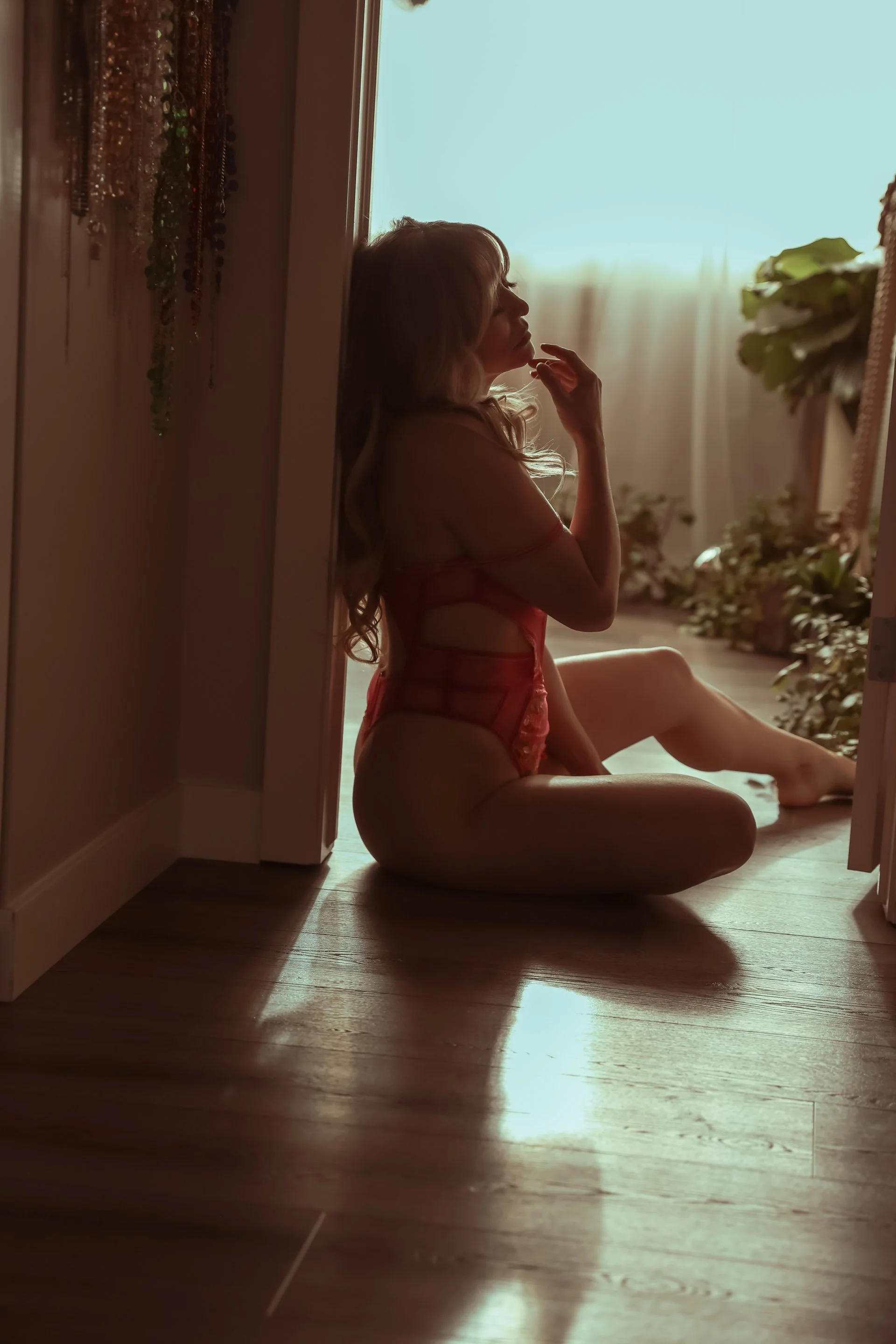 Woman laying on floor in sunlight, pink bodysuit, Edmonton boudoir studio