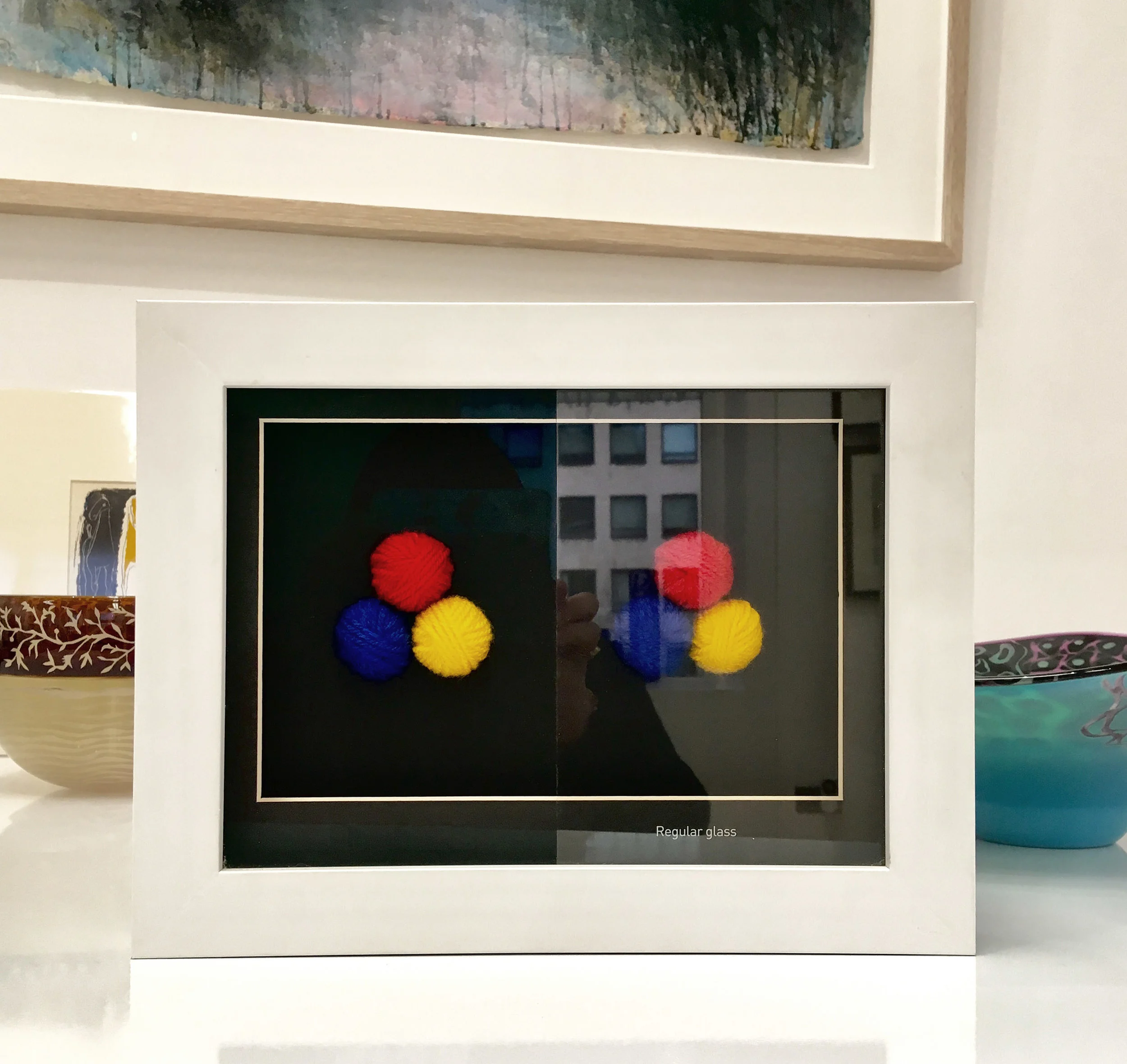 A sample highlighting the difference between regular glass and one of our specialist anti-reflective options.