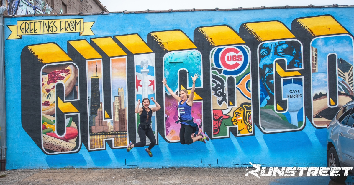 Chicago runners jumping in front of Chicago mural Chicago Marathon spectators