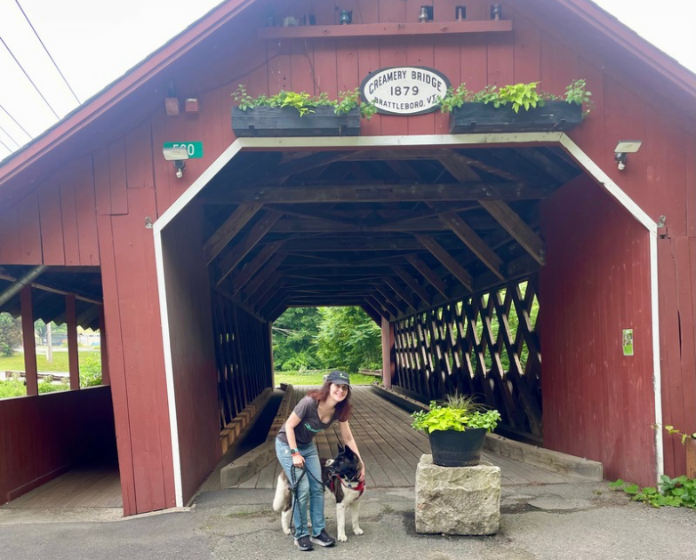 woman and her akita dog by a covered bridge in Vermont